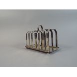 A Silver Six Slice Toast Rack with Brown Feet.
