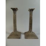 A Pair of Silver Corinthian Column Candlesticks on Stepped Square Bases.