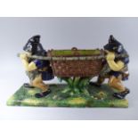 A Continental Majolica Planter in the Form of Two Gnomes Carrying Wicker Basket.