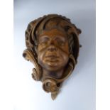 A 19th Century Black Forest Carved Lindenwood Wall Bracket Modelled as a Putti's Face Surrounded by