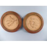 A Pair of Framed Circular Terracotta Wall Hanging Plaques Decorated in Relief with Angels Carrying