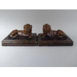A Pair of Early 19th Century Treacle Glazed Stoneware Studies of Recumbent Lions set on Rectangular