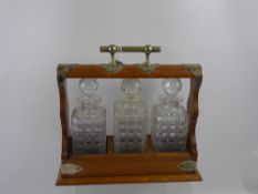 An Oak Cased Tantalus, with three cut glass decanters and a key.