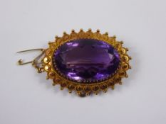 An Edwardian 15 ct Gold and Amethyst Brooch. The amethyst set in a disc and beaded mount, the