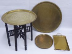 A Persian Brass Tray, on an ebonised stand, together with three Persian tea trays. (4)