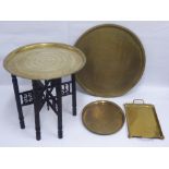 A Persian Brass Tray, on an ebonised stand, together with three Persian tea trays. (4)