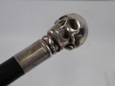 A Silver Topped Rose Wood Cane, the cane handle in the form of a skull, the cane having a Stirling