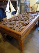 An Impressive Indonesian Hand Carved Teak Dining Room Table, the table having a heavily carved inset