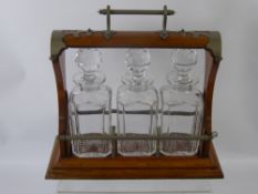 An Oak Cased Tantalus, comprising three cut glass bottles, the case decorated with metal corners.