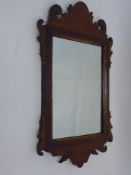 Two Mahogany Framed Wall Mirrors, together with an oval bevelled glass mirror. (3)