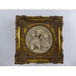 A Circular Marble Plaque, carved in relief, depicting affectionate children, within a gilt wood