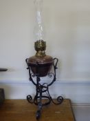 An Antique Copper and Brass Oil Lamp, held within a wrought iron support, approx 66 cms