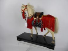 A Japanese Child's Toy, a felt pony with saddle and lacquer stirrups, raised on a black lacquer