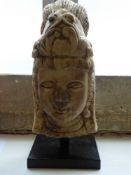 An Antique Burmese Carved Marble Buddha Head, supported on a square black plinth, approx 43 cms