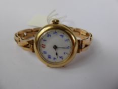 A Lady's 15 ct Gold Wrist Watch, the watch having a white enamel face with blue numerals and red