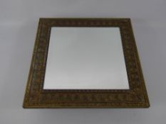 An Edwardian Arts and Crafts Mirror, the mirror having bevelled glass with brass frame depicting