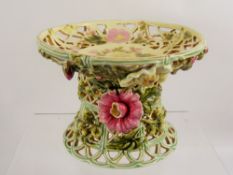 A Hand Painted Compote Centrepiece, the floral encrusted bowl resting on a basket weave pedestal,