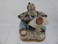 A Japanese Seated Nodding Head Figure, holding a cup and fan, approx 19 cms high.