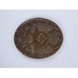 A Small WWII Bronzed Oval Badge, depicting crossed swords and helmet with swastika emblem, awarded