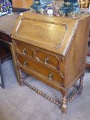 A Small Oak Drop-Front Writing Desk, fitted interior, with two drawers, raised on barley-twist