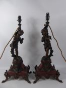 A Pair of Late 19th Century Bronzed Lamps Depicting Standing Cherubs, raised on a red marble base