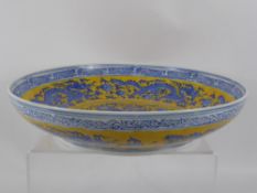 A Contemporary Blue and Yellow Chinese Ceramic Bowl, depicting chasing dragons, marks to base,