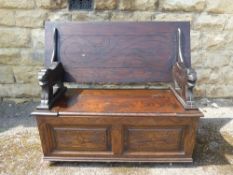 A Carved Mahogany Monk's Bench, with lion supports, storage cupboard beneath, label reads "Collyer's