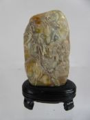 A Shoushan Stone, carved with a figure in a garden, approx 9 x 5 cms, raised on a oval wooden base.