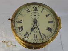 A Smiths Empire Brass Ships Clock, cream face with Roman dial, subsidiary second hand, with key.