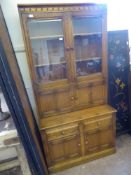 A Light Oak Ercol Glaze Fronted Dresser/Cupboard, with three shelves behind glaze fronted doors,