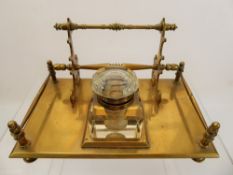 A Brass Ink Stand, the stand having one lidded glass inkwell, on a stand with three sets of pen