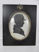 An Antique Silhouette Portrait, wearing a hat and fur collar in black wooden frame, verso there is a