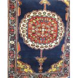 A Persian Woollen Rug, of blue and salmon colouring, depicting a floral medallion surrounded by a