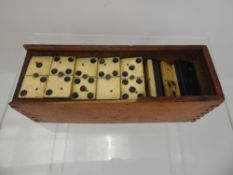 A Dominoes Set, made of bone and ebony in a wooden box without lid.