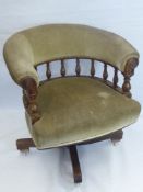 An Edwardian Captain's Chair, spindle back, swing movement with green upholstery on casters.