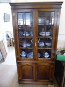 An Oak Reproduction Glaze Fronted Book Case, panelled sides with three shelves and a double cupboard