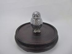 A White Metal Car Mascot, in the form of an owl on round wooden base, approx 10 cms inc. base.