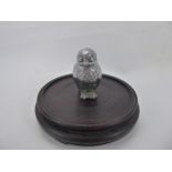 A White Metal Car Mascot, in the form of an owl on round wooden base, approx 10 cms inc. base.