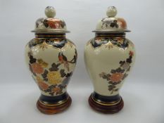 Two Chinese Lidded Jars on wooden stands, the jars depicting floral design, approx 41 cms.