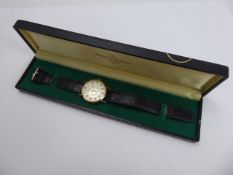 A Gentleman's 9ct Gold Bulova Longchamp wrist Watch. The watch having a silvered face with numeric