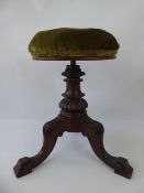 An Antique Mahogany Adjustable Piano Stool, upholstered in green velvet, on carved tripod legs.