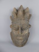 A West African Tribal Mask, carved wood, with broad features, expressive eyes and marks of