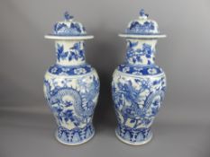A Pair of Chinese Late 18th/Early 19th Blue/White Vases and Covers, hand painted with chasing