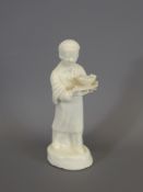 A White Porcelain Boy holding a plate and bowl of fish, approx 13 cms.