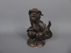 A Chinese Bronze Foo Dog, resting with its paws on a ball of string, approx 12 cms.
