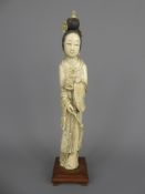 A 19th Century Ivory Okimono, finely carved as a Geisha depicted standing in long robes holding a