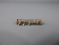 A 9 ct Yellow Gold Music Stave Brooch, the brooch having a rose cut dias, 1.8 mm cabachon emerald,