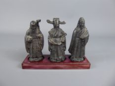 Three Chinese Figures, inset on a wooden base, approx 10 cms.