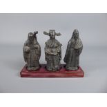 Three Chinese Figures, inset on a wooden base, approx 10 cms.