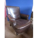 An Antique Howard Brown Leather Chair (original leather) with turned wood legs on brass castors,
